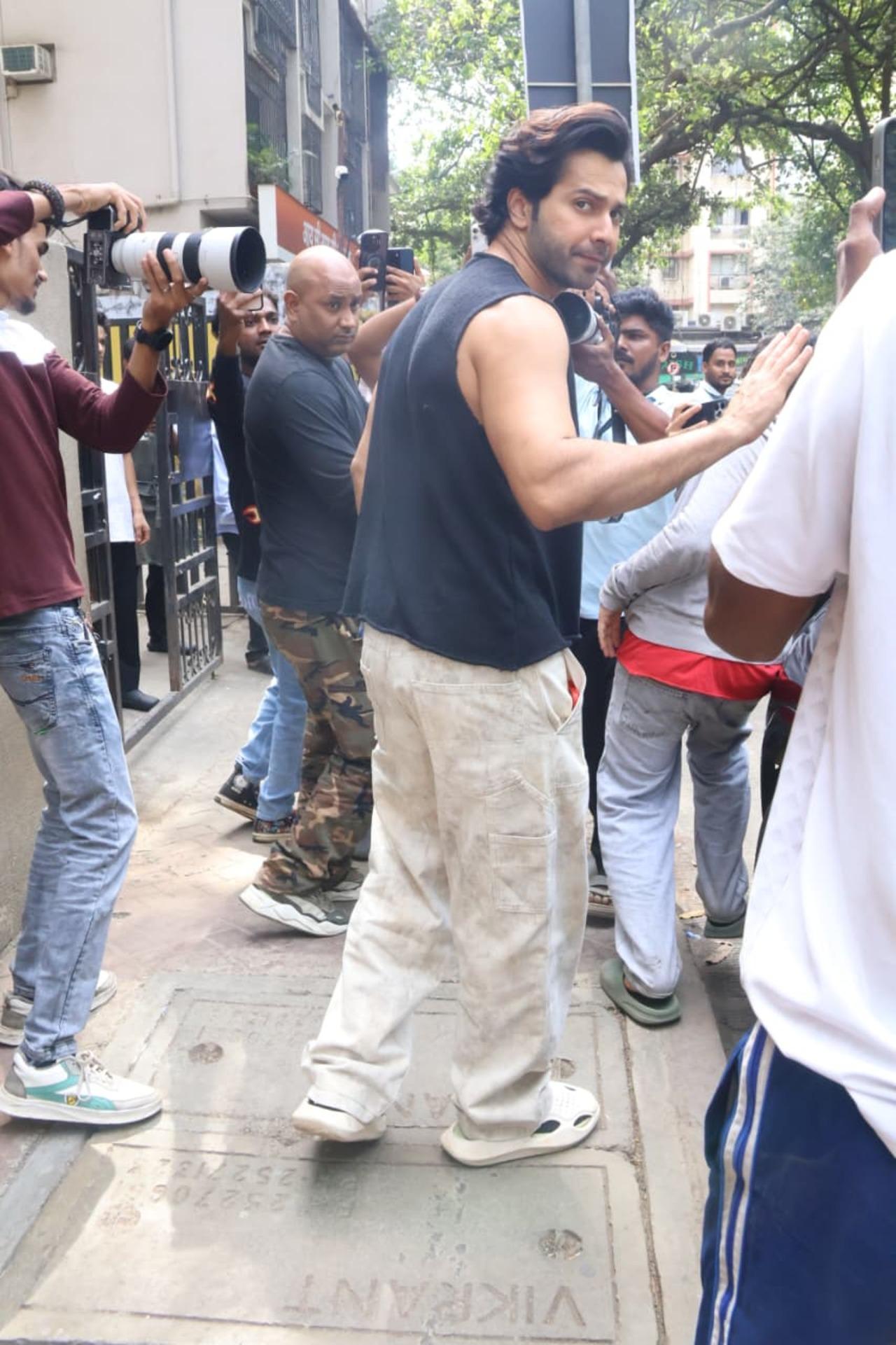 Varun opted for a black sleeveless t-shirt paired with beige pants and sneakers.